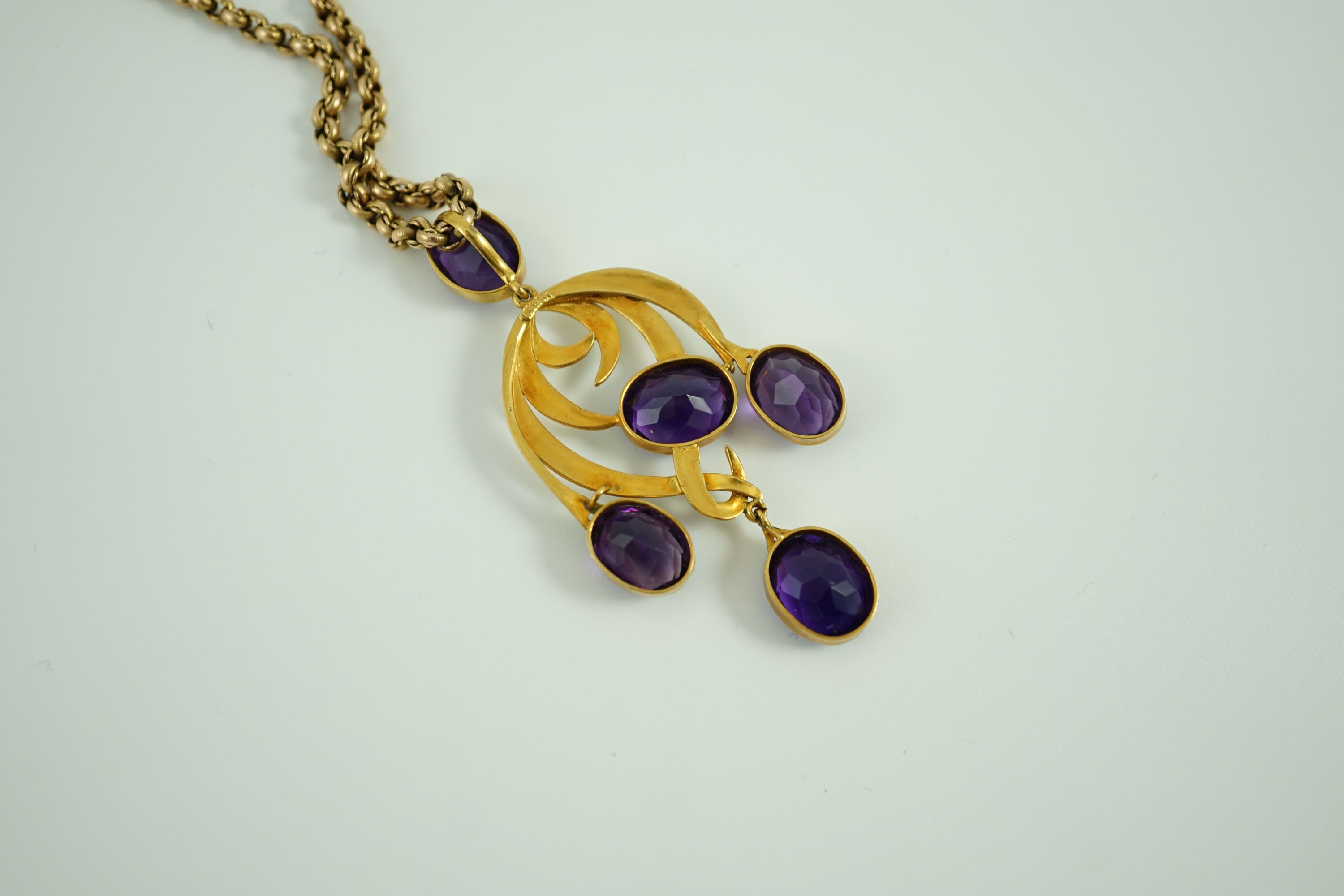 An early 20th century continental gold, enamel and five stone oval cut amethyst set drop pendant, of scrolling design